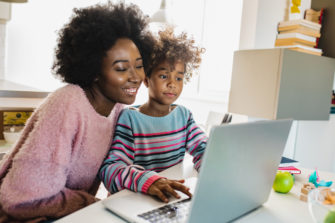 African American mother and daughter look at a laptop screen together