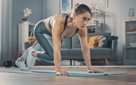 Mulher apta com sutiã esportivo e leggings fazendo alpinismo em um tapete de ioga