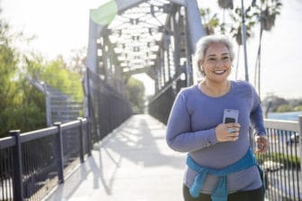 A mature woman power walks on bridge to achieve smart fitness goals.