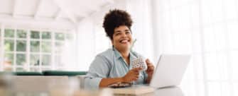 Happy woman sits at her desk, thinking of her work-life balance goals.