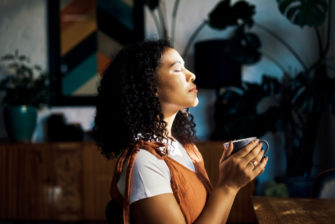 Woman practices meditation while drinking a cup of coffee.