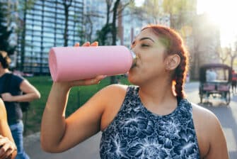 Woman drinks from water bottle to stay hydrated after a run.