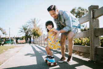 Father helps daughter skateboard as part of their weekly physical activity.