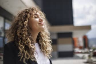 Woman steps outside to enjoy the sunshine during her work day, improving wellness.