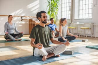 A group practices yoga in a class setting as part of their stress-reducing exercise routine.