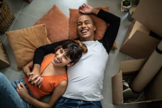 Happy couple lays on bed together, showing the benefits of relationships to your well-being.