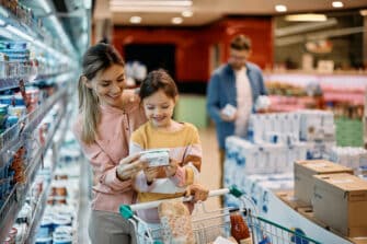 Mom and daughter read food labels while shopping to establish healthy eating habits.